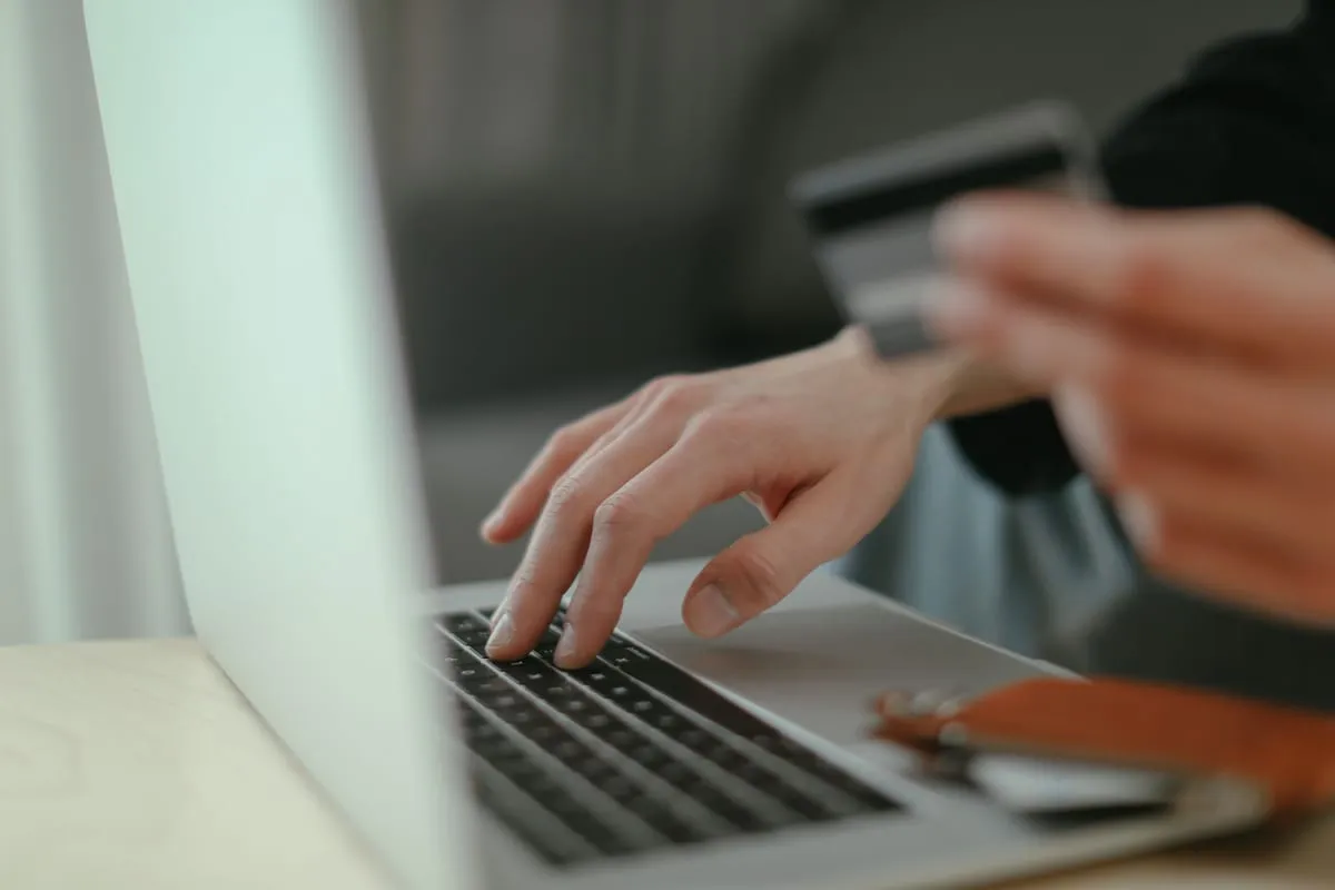 Hands typing on a laptop with an online store on screen